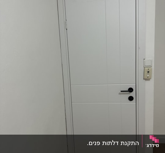 דלת לבנה עם ידית שחורה וקיר לבן